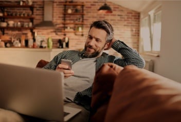 Mann sitzt auf Sofa am Laptop