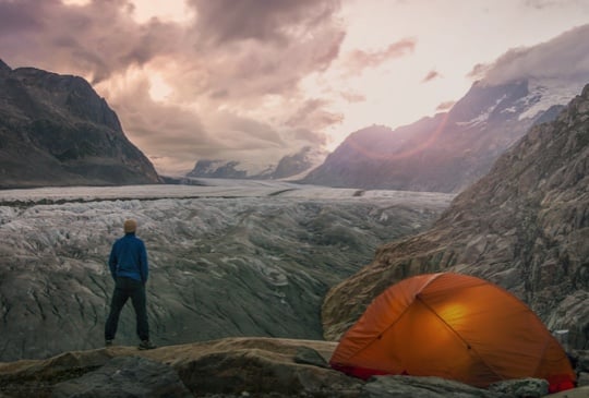 Mann steht vor einem Gletscher mit Bergen