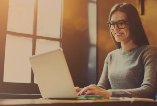 Frau mit Brille schreibt an einem Laptop